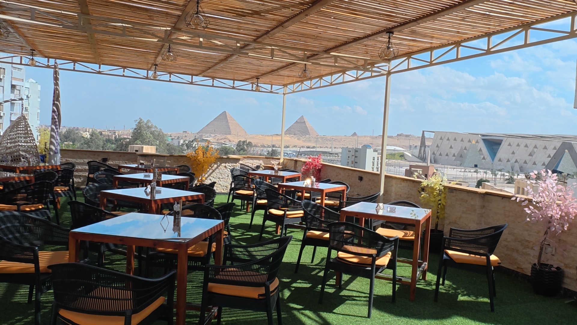 Rooftop terrace at Grand View overlooking the Great Pyramids of Giza and the Grand Egyptian Museum by day